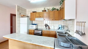 Cocina compacta con armarios de madera, un refrigerador blanco, un microondas, una estufa y un lavamanos.