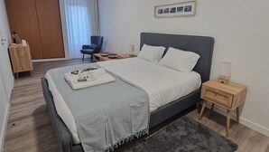 A modern bedroom with a bed, bedside tables, a chair, and a wardrobe.