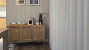 A room with a wooden cabinet, two framed pictures, a vase with flowers, and a wooden bench.