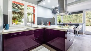 A modern kitchen with a large island, a built-in oven, and a window with a view of greenery.