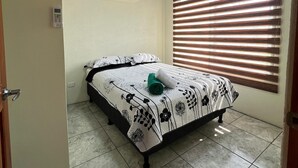 Een slaapkamer met een bed, een airconditioning, een raam met jaloezieën en een deur.
