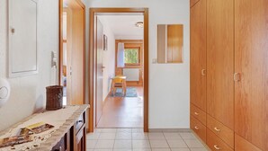 A hallway with a wooden wardrobe, a table with magazines, a wicker basket, and a chair. - Apartment 'Wiesenblick' with Shared Terrace, Shared Garden and Wi-Fi (Schramberg)