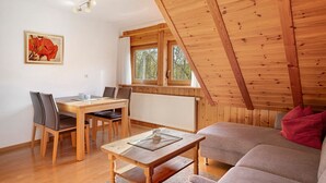 A wooden interior with a dining table, chairs, a sofa, and a window with a view of trees. - Apartment 'Gartenblick' with Shared Terrace, Shared Garden and Wi-Fi (Schramberg)
