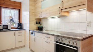 A modern kitchen with wooden cabinets, a built-in oven, and a countertop with a coffee maker. - Apartment 'Gartenblick' with Shared Terrace, Shared Garden and Wi-Fi (Schramberg)