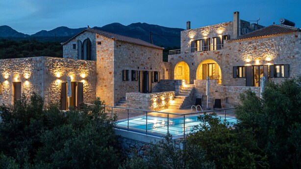 A stone building with a swimming pool, arched doorways, and outdoor lighting. - House of Muses: Erato (Lefktro)
