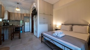 A compact hotel room with a bed, a small kitchenette, and a bathroom. - House of Muses: Erato (Lefktro)