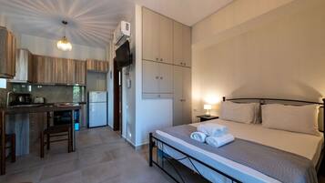 A compact hotel room with a bed, a small kitchenette, and a bathroom.
