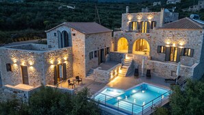 Une villa en pierre dotée d’une piscine, d’un espace extérieur aménagé et de plusieurs arcades.