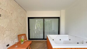 A modern room with a wooden table, a glass-topped coffee table, a wooden chair, a large sliding glass door, and a wooden hot tub. - Increible Studio Con Jacuzzi Naia C19 (Tulum)