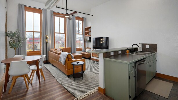 Un espacio habitable compacto con comedor, sofá, televisor y kitchenette.