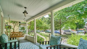 A covered porch with patterned floor and chairs, overlooking a street with parked cars and greenery. - Craftsman Oasis in Old Longmont (Longmont)