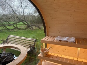 Eine Holzsauna mit Bänken und einem Tisch, ein Handtuch und ein Eimer mit einem Wasserschöpfer.