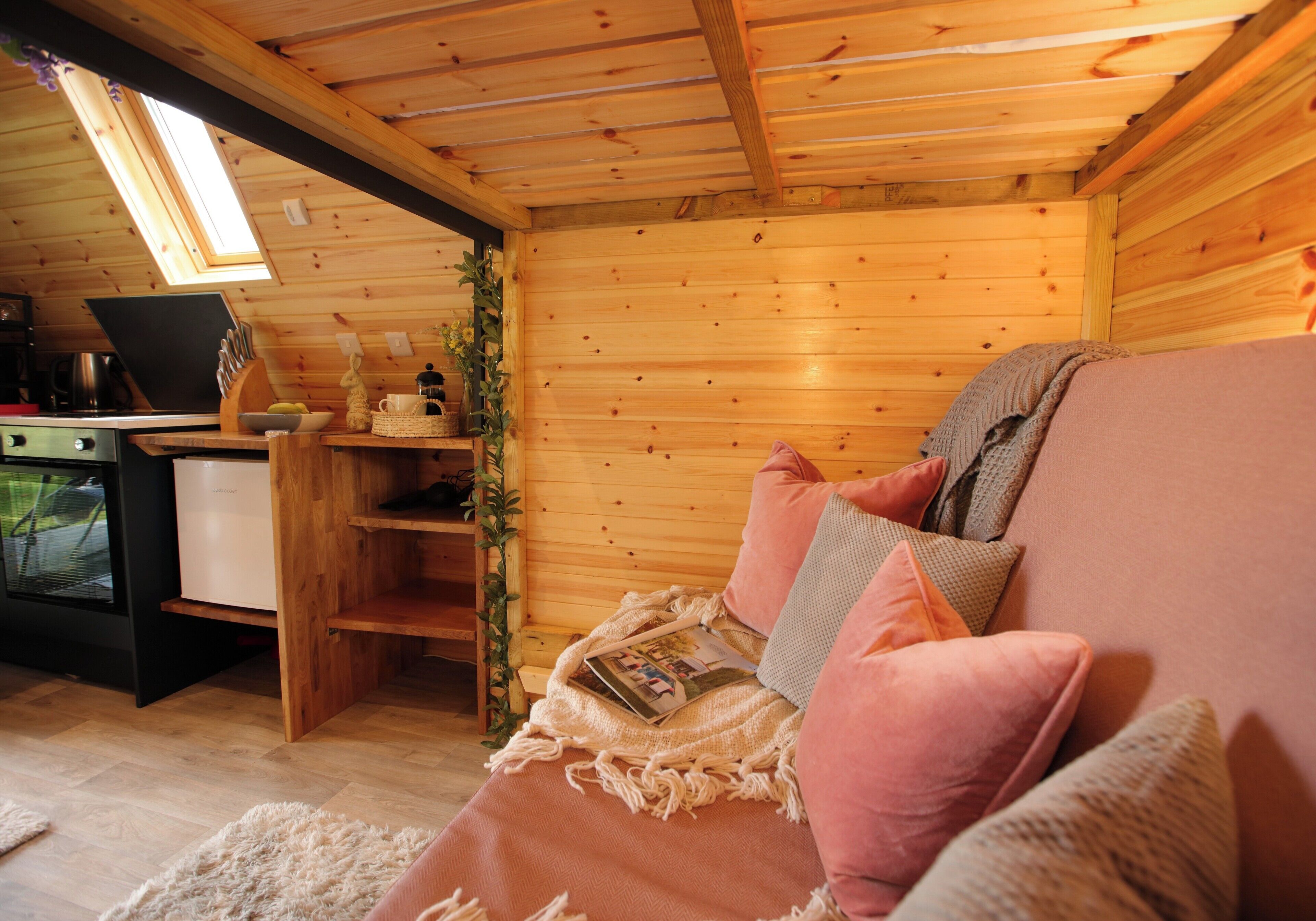 A cozy wooden cabin interior with a sofa, a small table, and a laptop.