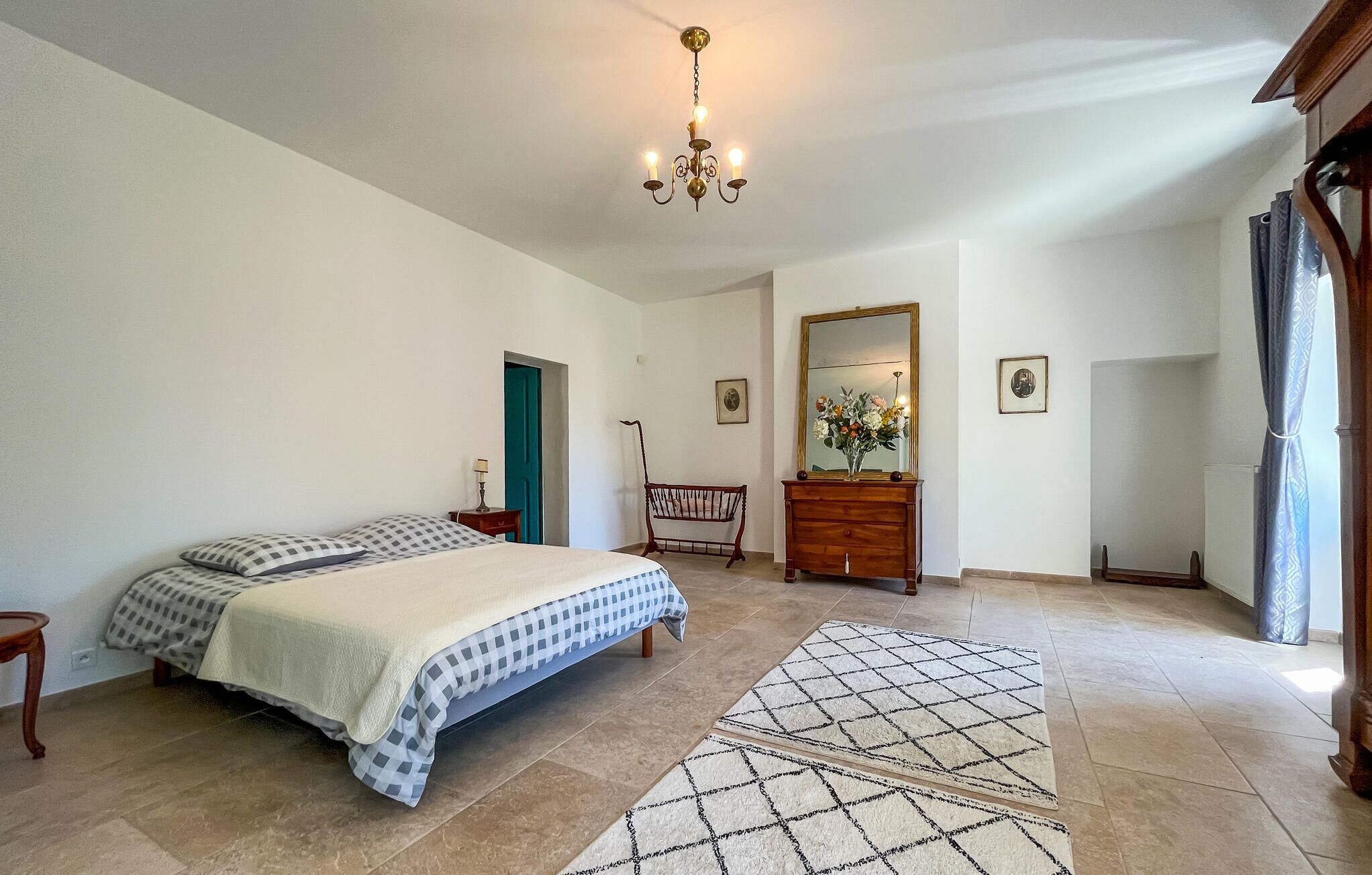 Een slaapkamer met een bed, een kaptafel, een spiegel en een kroonluchter.