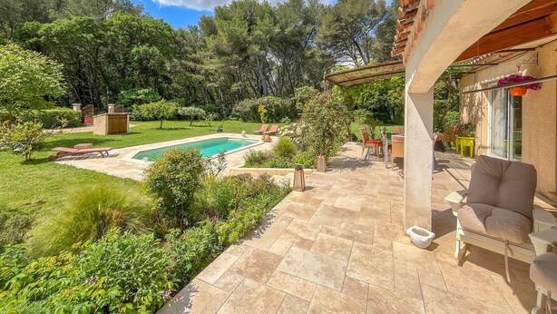 Ein Garten mit Swimmingpool, Terrassenmöbeln und einer Pergola.