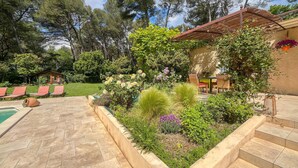 Ein Garten mit Pool, Sitzgelegenheiten im Freien und einer Pergola.
