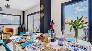 Een eetgedeelte met een tafel voor vier personen, grote ramen en uitzicht op de stad.