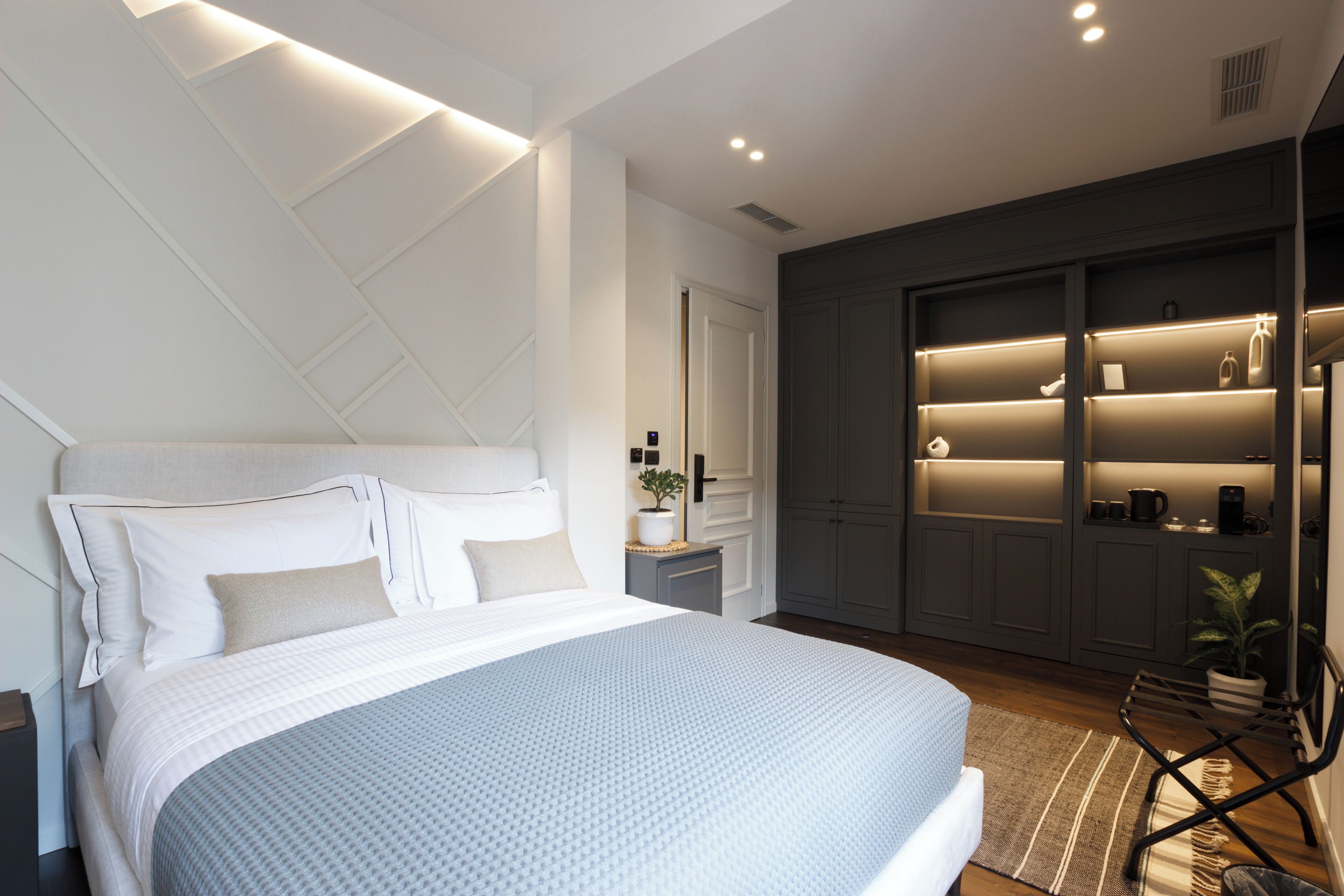Un dormitorio moderno con una cama grande, estanterías empotradas y una pequeña zona de estar.