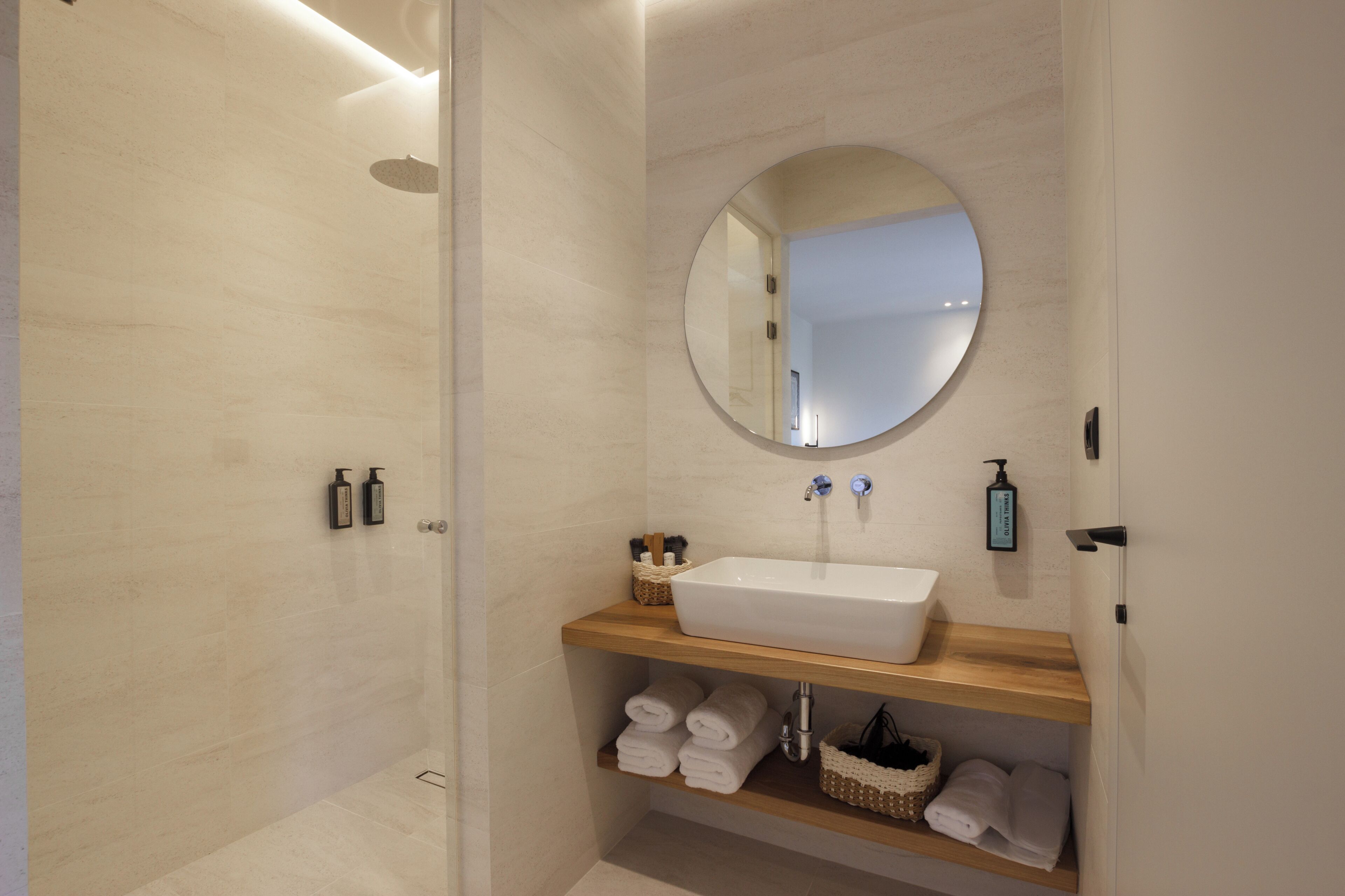 Une salle de bain moderne avec un grand lavabo, un miroir rond et un espace douche.