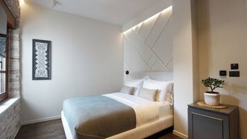 Un dormitorio moderno con una cama grande, un cabecero decorativo, una mesita de noche con una planta y una obra de arte enmarcada en la pared.