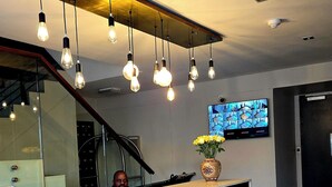 Ein Empfangsschalter mit Holz-Fischgrätmuster, eine Vase mit gelben Blumen und ein Fernsehbildschirm, der ein Muster zeigt.