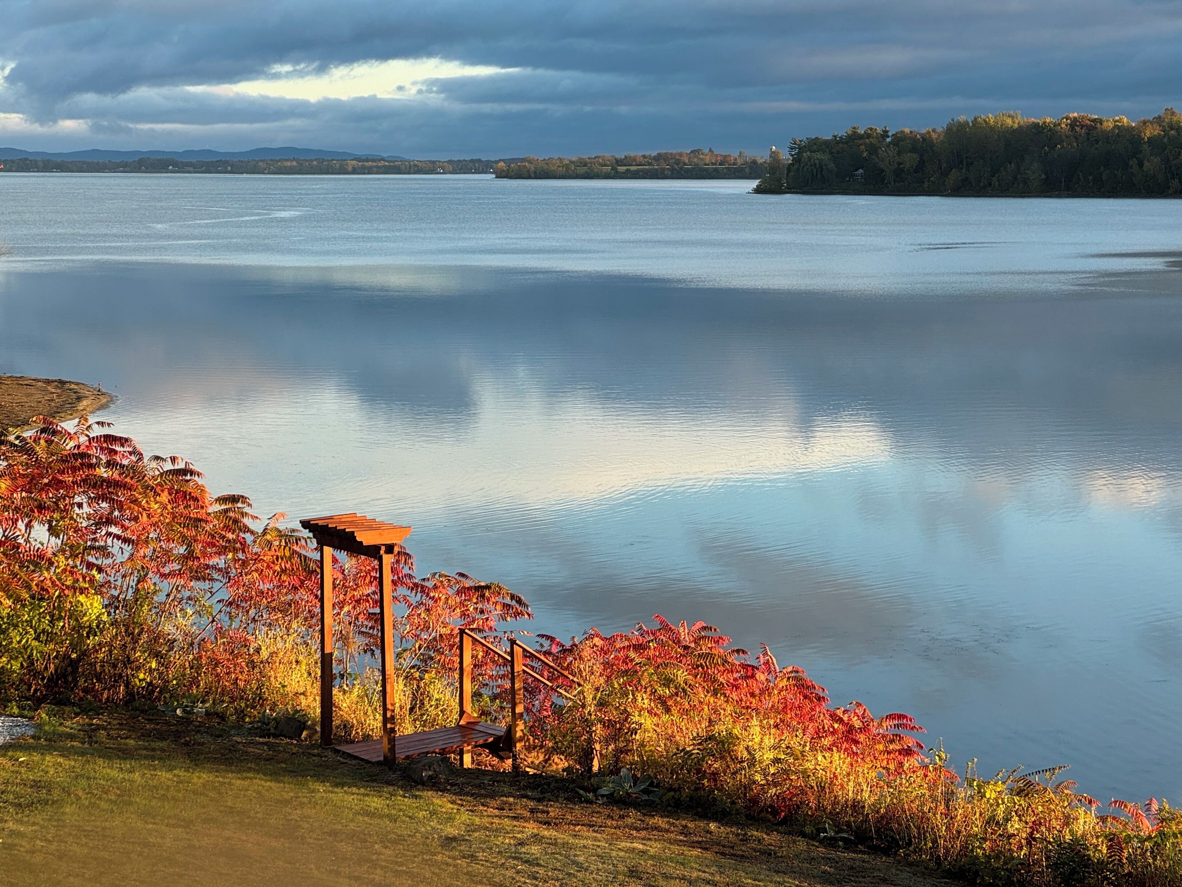 A lakeside view with a gazebo and autumn foliage.