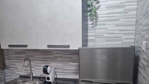 Una cocina moderna con un refrigerador de acero inoxidable, un lavamanos empotrado y una cafetera.