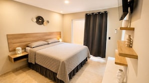 A bedroom with a bed, bedside tables, a nightstand, a wall-mounted TV, and a door with a curtain. - Modern and luxurious for 8 (3 bedrooms with their own bathroom) (San Pedro Sula)