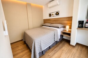 Ett hotellrum med en säng, ett sängbord, en lampa och en luftkonditioneringsanläggning.