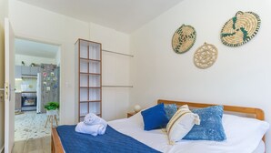A bedroom with a bed, pillows, a wooden wardrobe, and wall decorations.