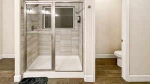 Une salle de bain avec une douche à parois de verre, des toilettes et une porte blanche.
