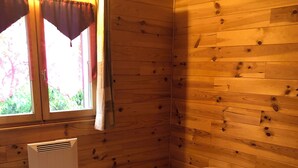 Een houten kamer met een bed, een raam met gordijnen en een wandradiator.