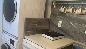 A laundry area with stacked washing machines and a dishwasher. - 
Nested in beautiful south facing garden studio available for rent (West Vancouver)