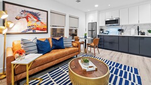 A modern living room with a leather sofa, a coffee table, and a dining area with chairs.