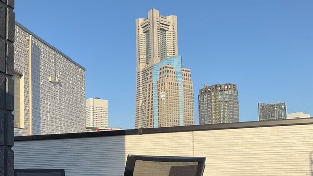 Terraza en la azotea con mesa y sillas, con vistas a un paisaje urbano de edificios altos.