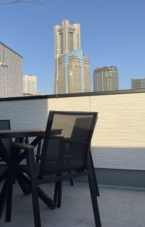 Une terrasse sur le toit, avec une table et des chaises, d’où l’on peut admirer le panorama de la ville et ses nombreux immeubles.