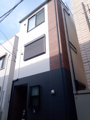 A multi-story building with a mix of brick and white walls, large windows, and visible electrical wiring.
