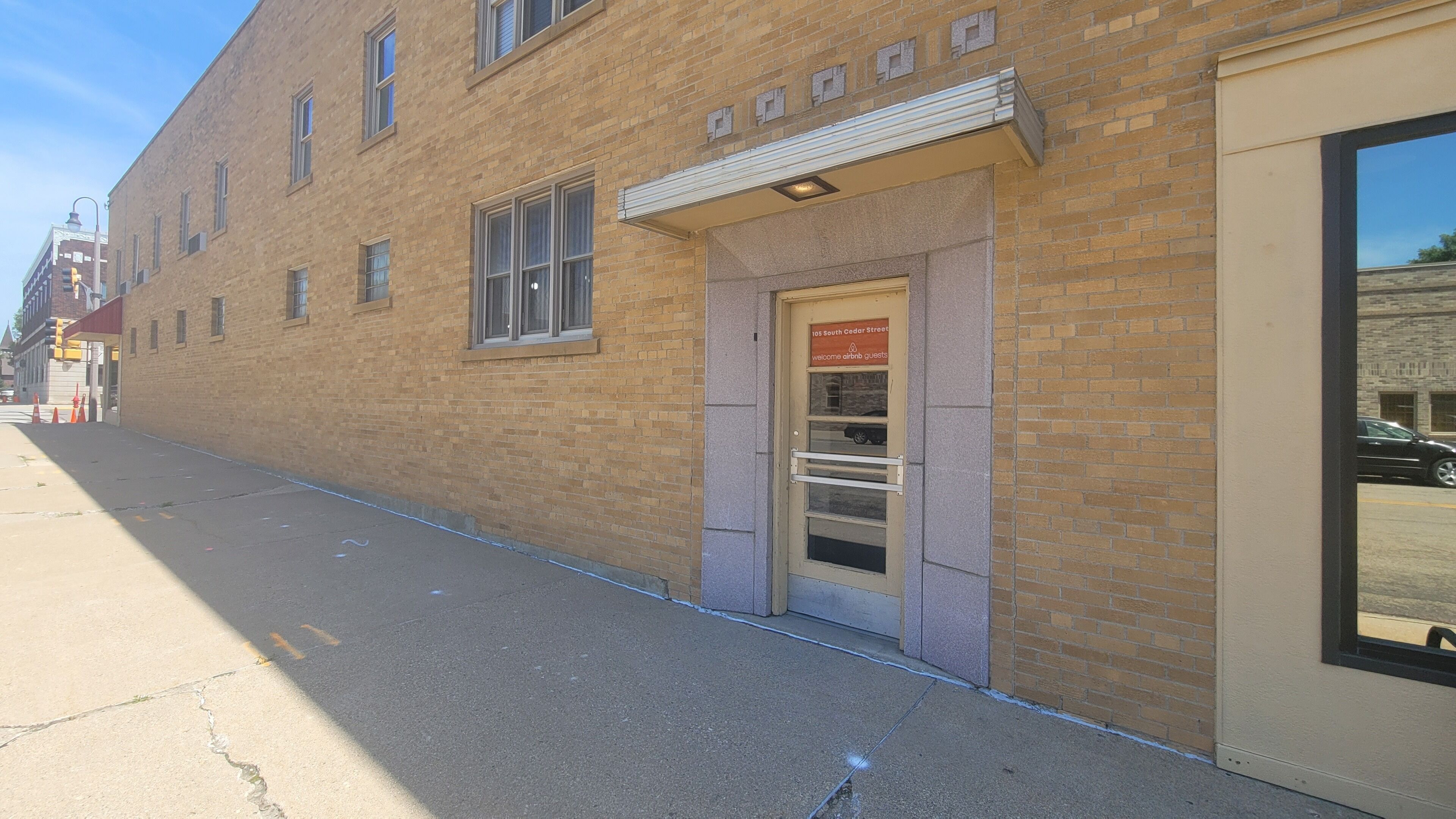 Un edificio de ladrillo con una puerta que indica “105 South Cedar Street” y una ventana encima.