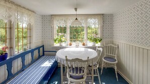 A room with a round table, white chairs, a blue bench, and patterned wallpaper.