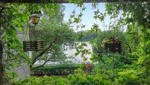 A garden with a wooden pergola, hanging lanterns, and lush greenery.