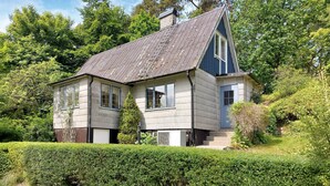A two-story house with a steeply pitched roof, a chimney, and a small attached garage.