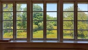 A room with a large window overlooking a green landscape.