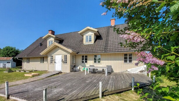 A two-story house with a wooden deck, a front door, and a small porch area.