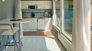 A compact kitchen with a microwave, coffee maker, and a small dining area with a table and chairs. - Awesome home in Sturkö with sauna (Sturkö)