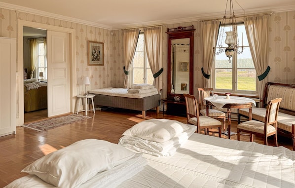 Une chambre à coucher avec un lit, une table, des chaises, un miroir et une vue sur l’extérieur.