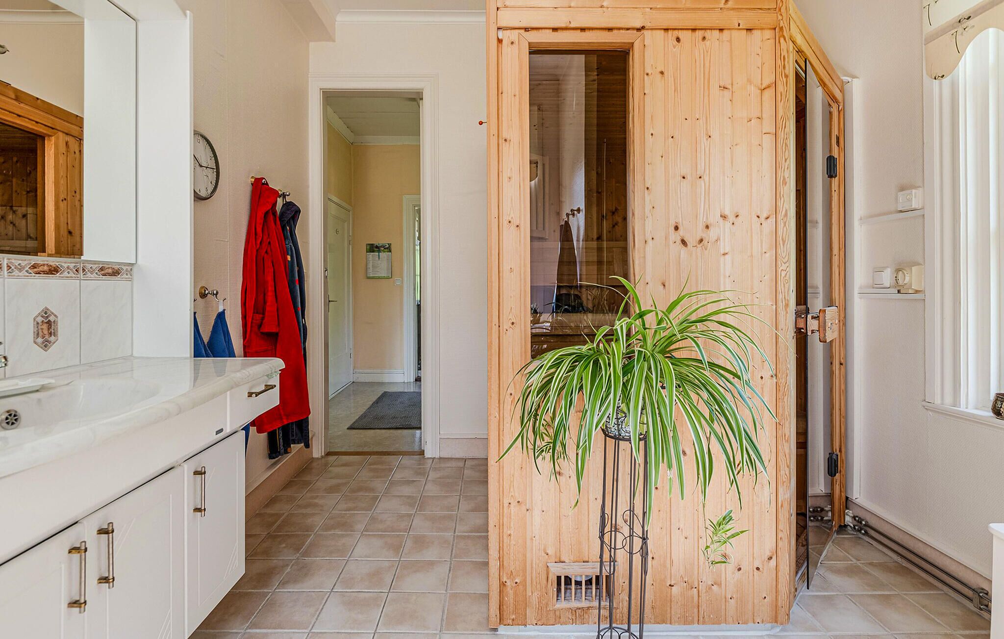 Eine Küche mit weißen Schränken, einer Holztür und einem Blumentopf.