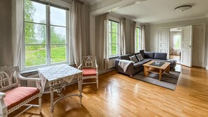 A spacious living room with a wooden floor, a dining table with chairs, a sofa, and a coffee table. - Nice apartment in Mullsjö with sauna (Mullsjö)