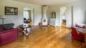 A spacious living room with a herringbone wooden floor, a red sofa, a small round table, and a white cabinet. - Nice apartment in Mullsjö with sauna (Mullsjö)
