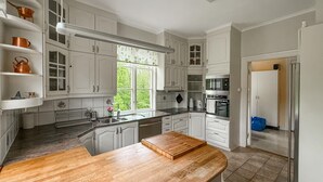 A kitchen with white cabinets, a wooden countertop, a window with a view of greenery, and a built-in oven. - Nice apartment in Mullsjö with sauna (Mullsjö)
