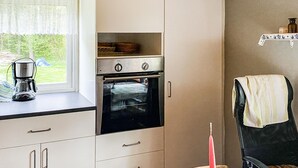 A kitchen with a built-in oven, a coffee maker on the counter, and a window with a view of greenery outside. - 2 bedroom awesome home in Gislatorp (Gislatorp)
